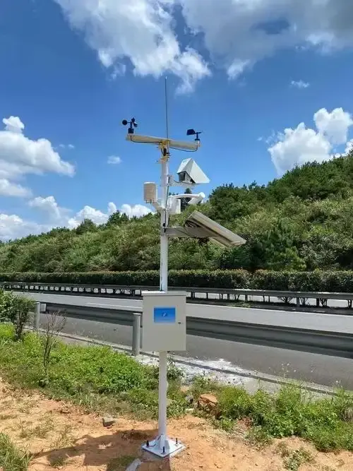 Pole-mounted non-invasive optical road state sensor monitoring highway asphalt conditions during winter freeze.