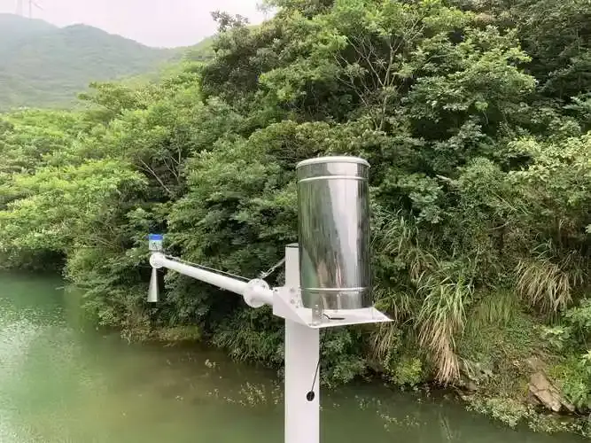 Close-up of an industrial stainless steel tipping bucket rain gauge with debris filter.